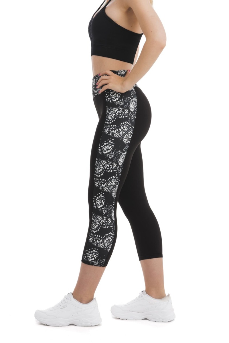 Črne capri pajkice z abstraktnim vzorcem metuljem v beli barvi ob straneh hlačnic in na pasu