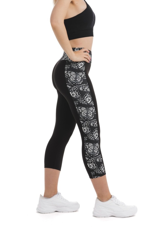 Črne capri pajkice z abstraktnim vzorcem metuljem v beli barvi ob straneh hlačnic in na pasu